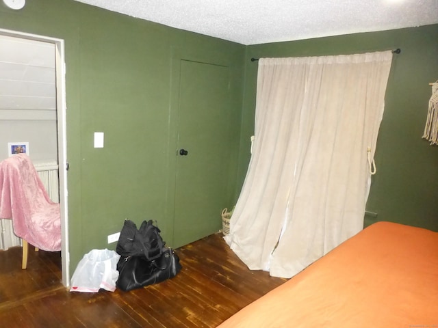 bedroom with dark hardwood / wood-style flooring and a textured ceiling