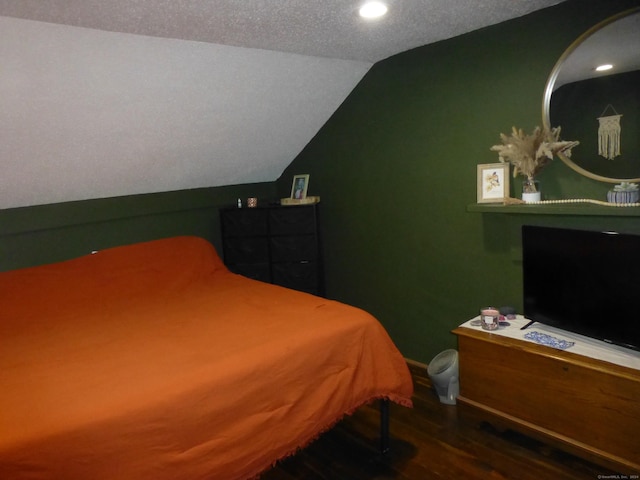 bedroom with a textured ceiling, lofted ceiling, and dark wood-type flooring