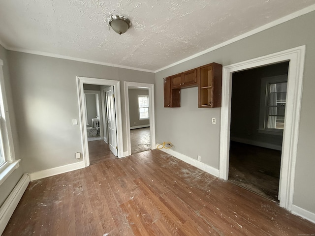 empty room with dark hardwood / wood-style flooring, ornamental molding, and baseboard heating