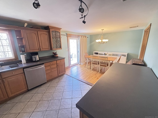 kitchen with sink, hanging light fixtures, stainless steel dishwasher, a notable chandelier, and light tile patterned floors