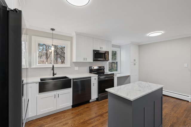 kitchen with sink, stainless steel appliances, white cabinets, a baseboard heating unit, and a kitchen island