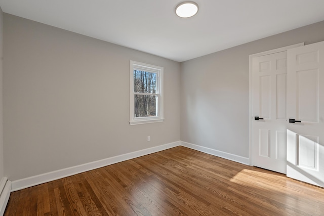 spare room with baseboard heating and hardwood / wood-style flooring