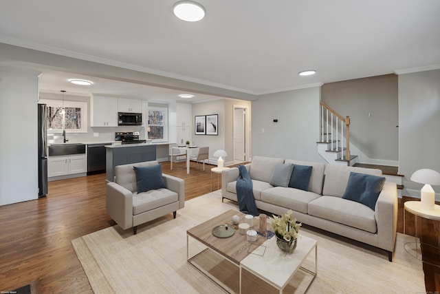 living room featuring crown molding, sink, and light hardwood / wood-style flooring