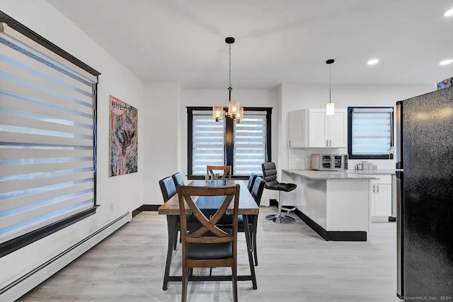 dining space featuring a baseboard radiator, an inviting chandelier, plenty of natural light, and light hardwood / wood-style floors