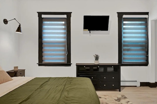 bedroom featuring baseboard heating and light hardwood / wood-style flooring