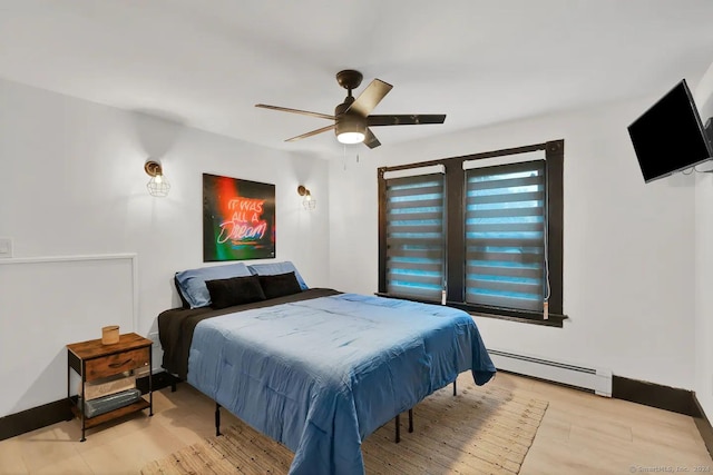 bedroom with ceiling fan, light wood-type flooring, and a baseboard heating unit