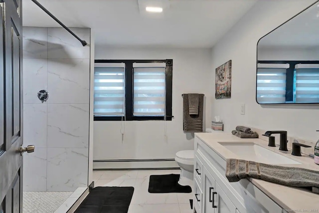 bathroom with a tile shower, vanity, toilet, and a baseboard heating unit