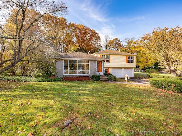 tri-level home with a garage and a front lawn