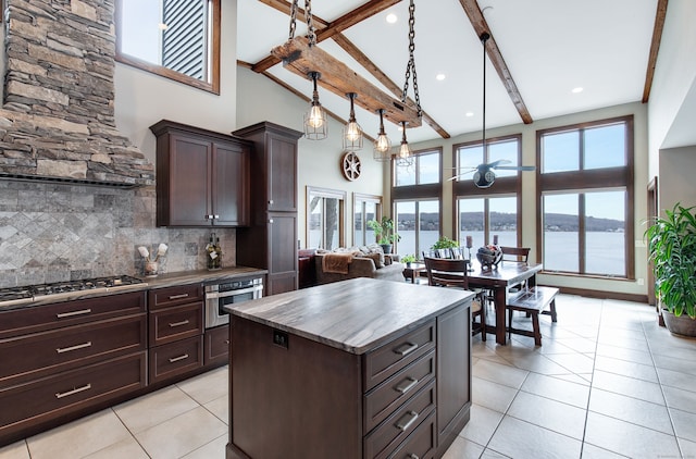 kitchen featuring a center island, backsplash, high vaulted ceiling, a water view, and beam ceiling