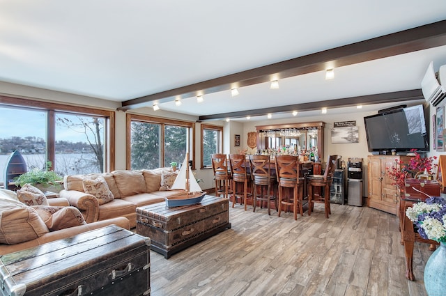 living room with a wall mounted AC, beam ceiling, bar, and light hardwood / wood-style flooring