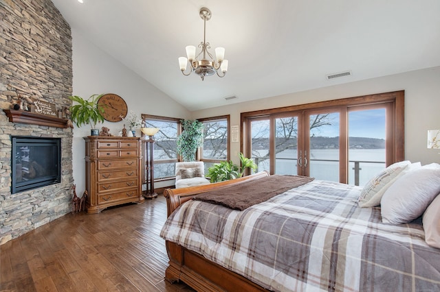 bedroom featuring access to exterior, a notable chandelier, a water view, and multiple windows