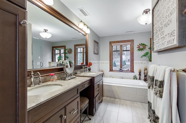 bathroom with vanity, tile patterned flooring, a relaxing tiled tub, and a healthy amount of sunlight