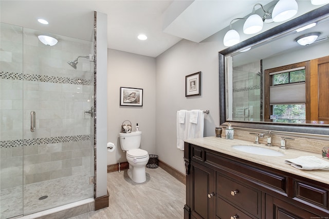 bathroom featuring vanity, a shower with shower door, and toilet