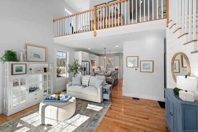 living room with light wood-type flooring and a towering ceiling