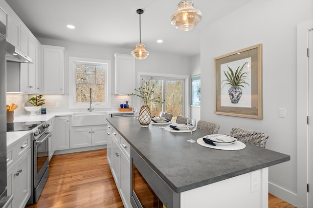 kitchen with a center island, sink, appliances with stainless steel finishes, decorative light fixtures, and white cabinetry