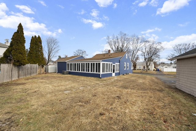 back of property with central AC unit and a sunroom