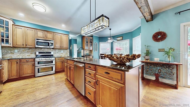 kitchen featuring pendant lighting, backsplash, a kitchen island with sink, appliances with stainless steel finishes, and beam ceiling