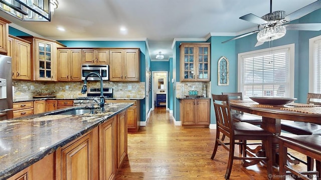 kitchen with dark stone countertops, backsplash, appliances with stainless steel finishes, and light hardwood / wood-style flooring