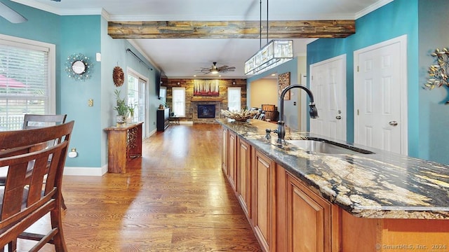 kitchen featuring ceiling fan, sink, hardwood / wood-style floors, dark stone counters, and pendant lighting