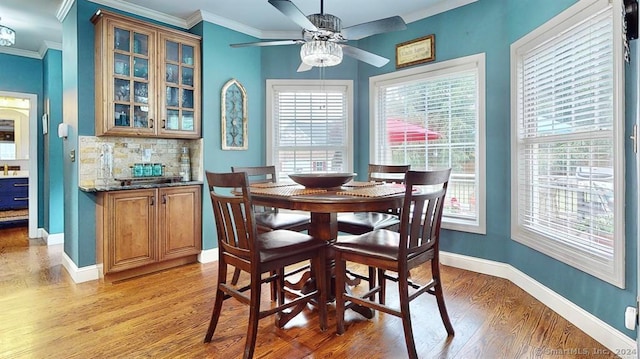 dining space with light wood-type flooring, a wealth of natural light, crown molding, and ceiling fan