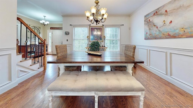 dining area with light hardwood / wood-style flooring, an inviting chandelier, and ornamental molding