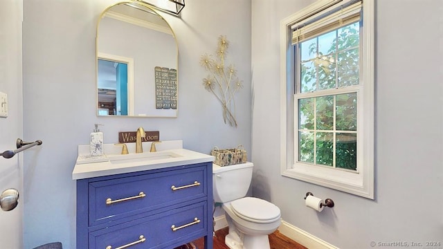 bathroom with toilet, vanity, and ornamental molding