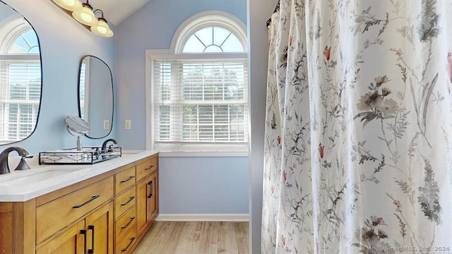 bathroom with hardwood / wood-style floors, vanity, curtained shower, and vaulted ceiling