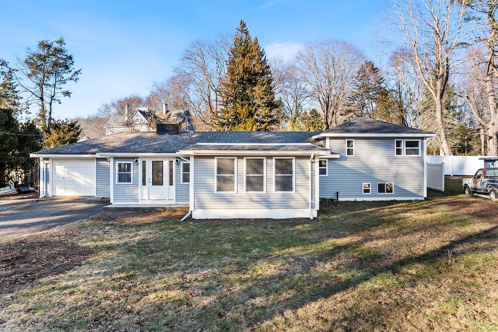 back of house with a garage and a lawn