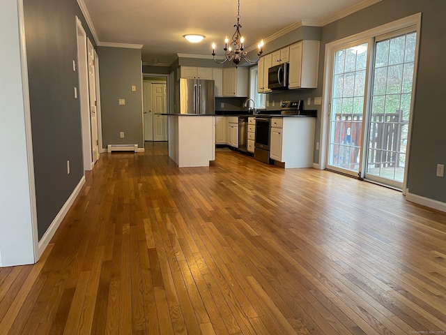 kitchen with stainless steel appliances, pendant lighting, wood-type flooring, a baseboard radiator, and white cabinetry