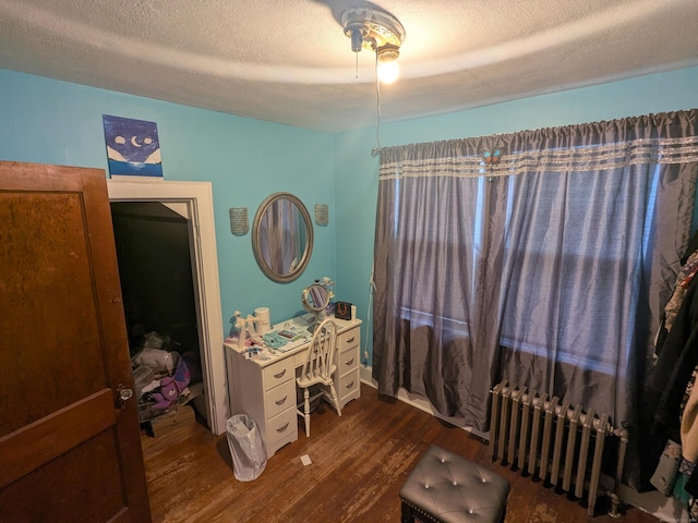 bedroom with dark hardwood / wood-style flooring, radiator heating unit, and a textured ceiling