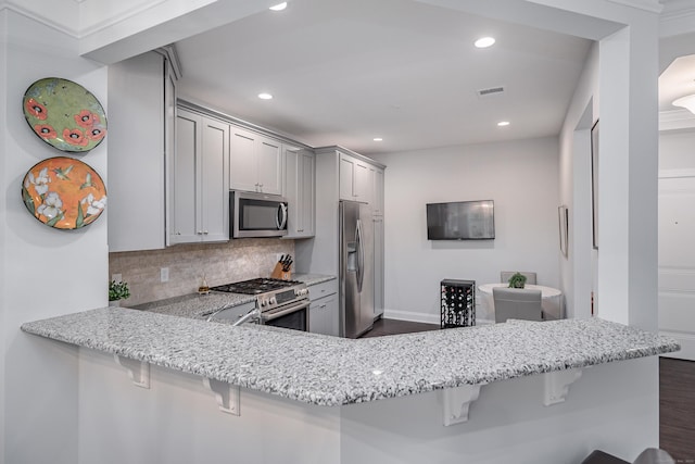 kitchen with a breakfast bar area, kitchen peninsula, tasteful backsplash, and stainless steel appliances