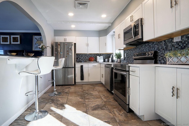 kitchen featuring stainless steel appliances, decorative backsplash, and white cabinets