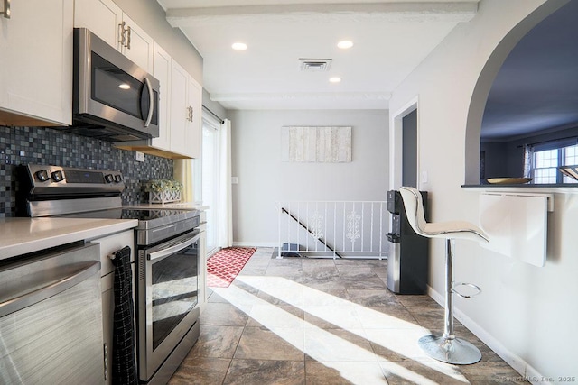 kitchen with white cabinets, stainless steel appliances, and tasteful backsplash