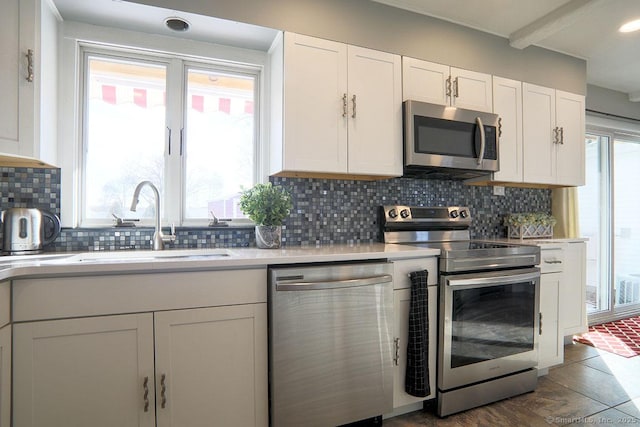 kitchen with plenty of natural light, stainless steel appliances, white cabinets, and sink