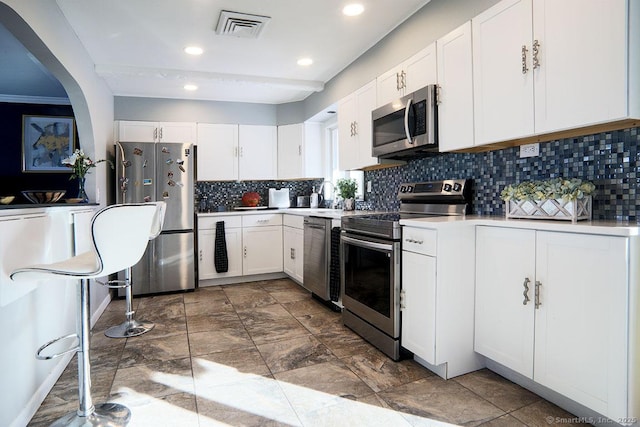 kitchen featuring stainless steel appliances, white cabinets, tasteful backsplash, and sink