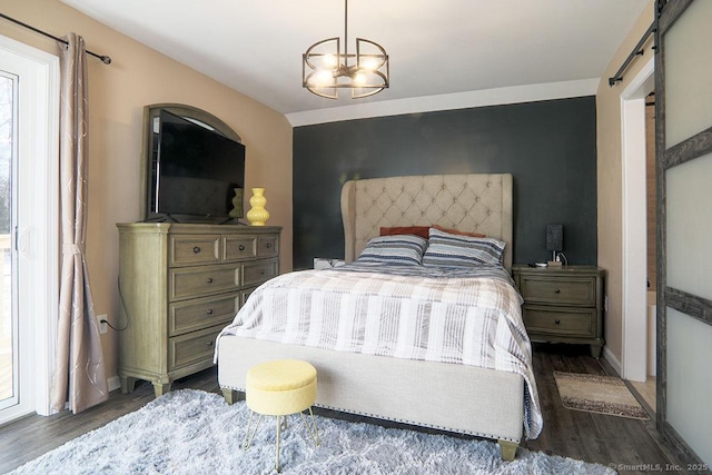 bedroom with a barn door, dark wood-type flooring, and a chandelier