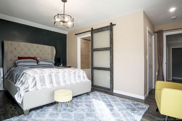 bedroom with an inviting chandelier, a barn door, and dark hardwood / wood-style floors