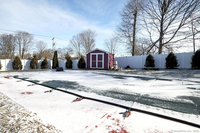 yard covered in snow with a storage unit and a covered pool