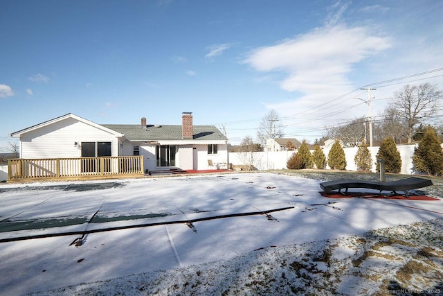 snow covered rear of property with a deck