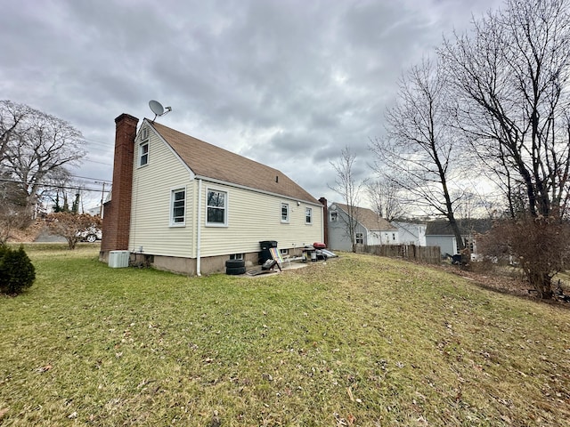 rear view of property featuring a lawn and central air condition unit