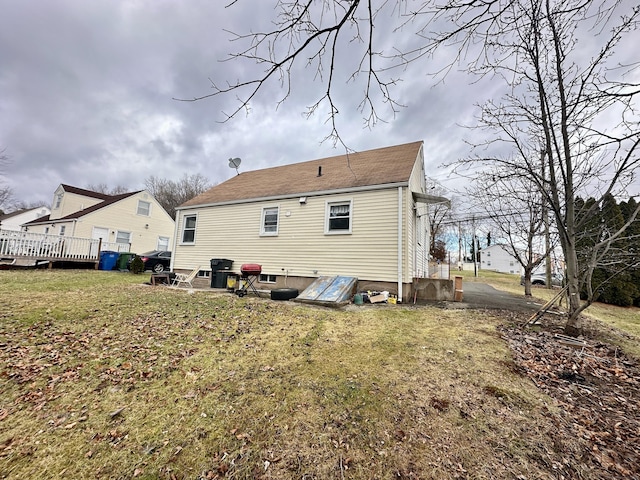 back of house featuring a lawn and a deck