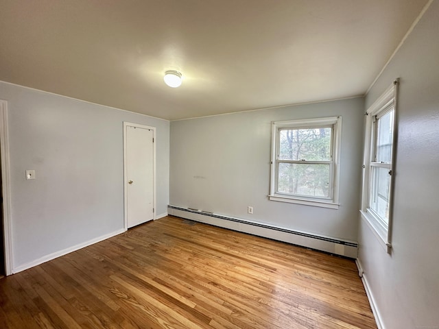 empty room with light hardwood / wood-style flooring and a baseboard heating unit