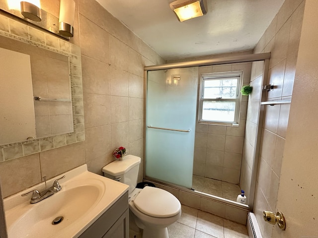 bathroom with baseboard heating, tile patterned floors, vanity, a shower with shower door, and tile walls