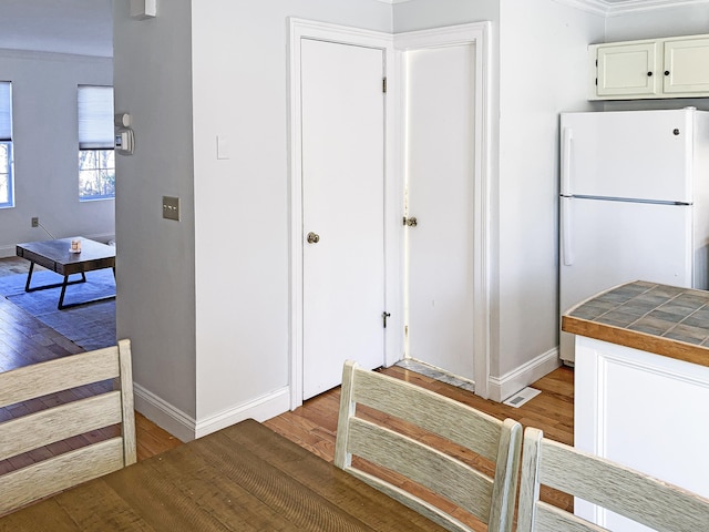 interior space with white cabinetry, tile counters, light wood-type flooring, and white refrigerator