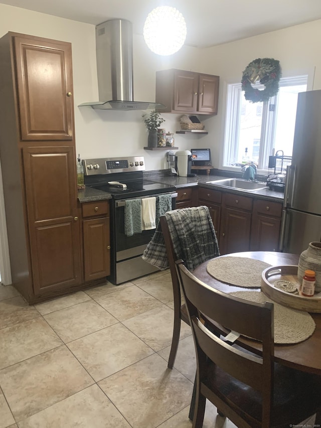 kitchen featuring sink, wall chimney exhaust hood, light tile patterned floors, appliances with stainless steel finishes, and dark brown cabinets