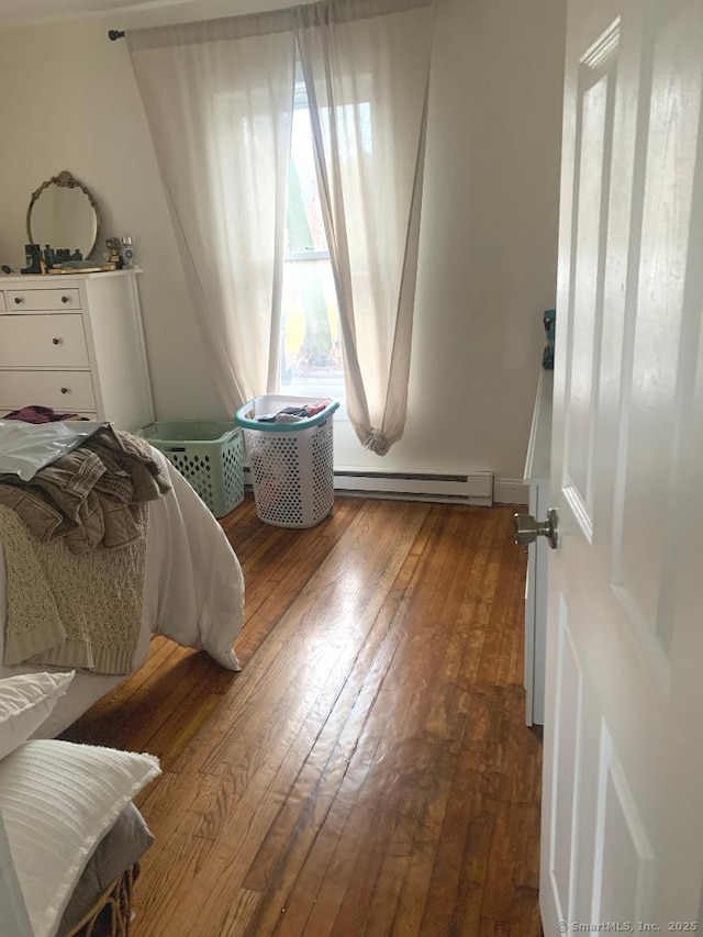 bedroom featuring wood-type flooring, multiple windows, and a baseboard radiator