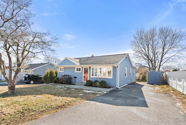 ranch-style house featuring a storage unit and a front yard