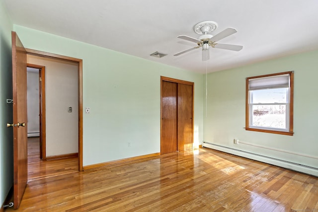 unfurnished bedroom with ceiling fan, a closet, a baseboard radiator, and light hardwood / wood-style floors