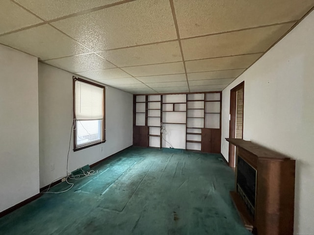 interior space featuring a paneled ceiling, built in features, and dark colored carpet