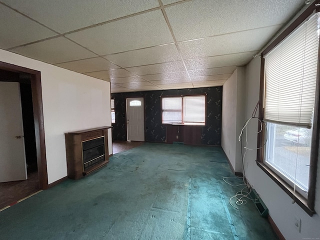 unfurnished living room with carpet and a drop ceiling